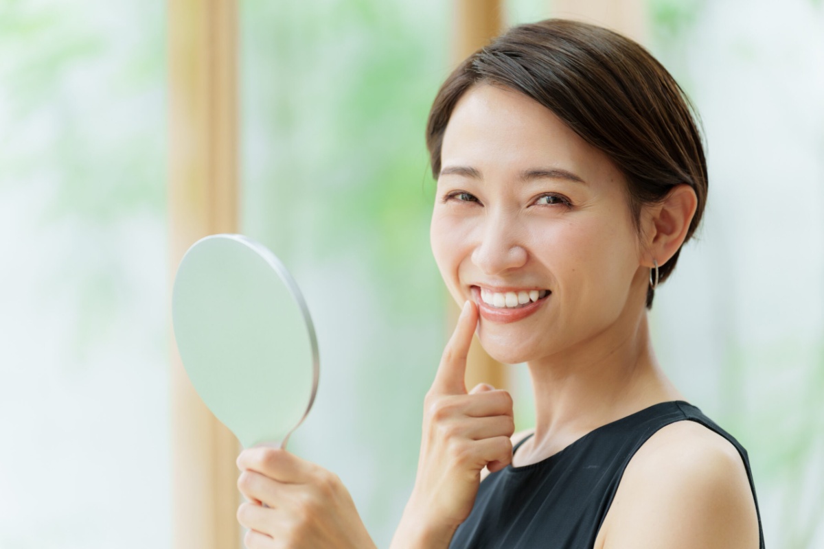 鏡を見てホワイトニングの効果を実感して喜ぶ女性
